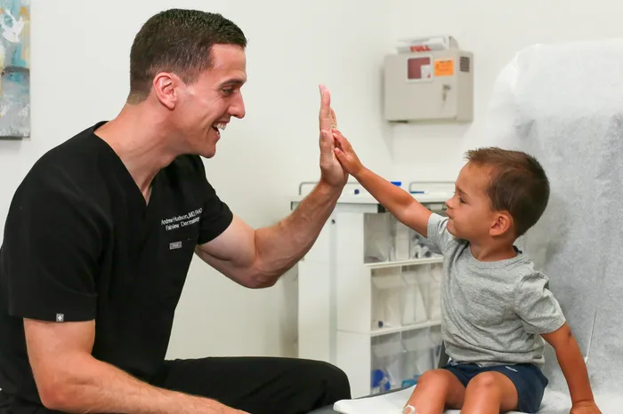 Dr. Hudson giving a high five to a young patient