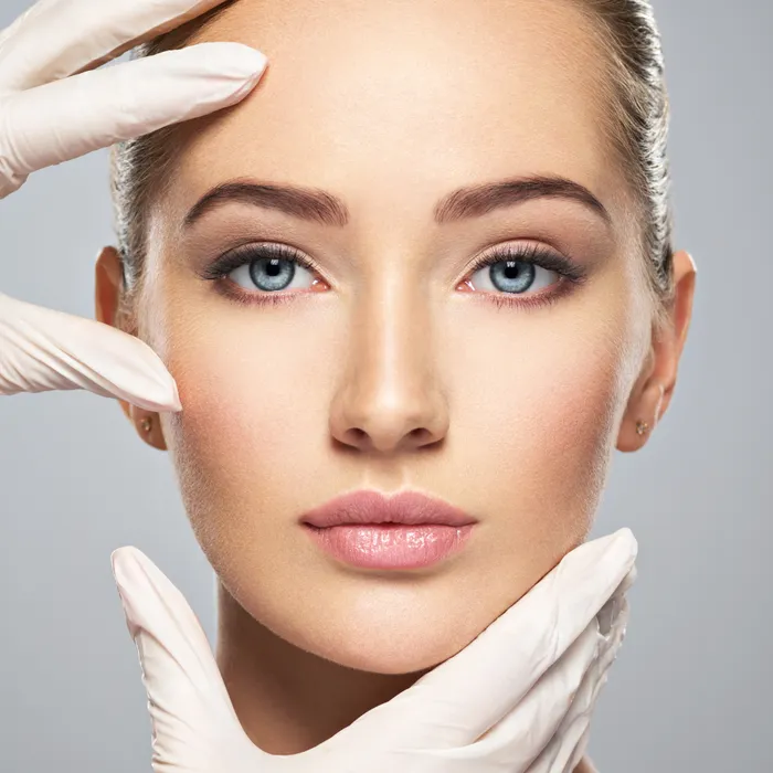 A symetrical woman's face with gloved hands framing it