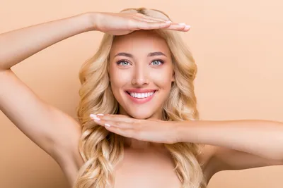 A smiling woman framing her face with her hands