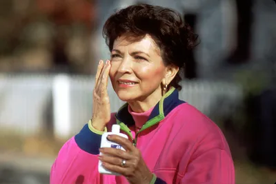 A woman applying sunscreen to avoid skin cancer